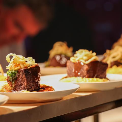Steak with onions on top being prepared in batches for the event