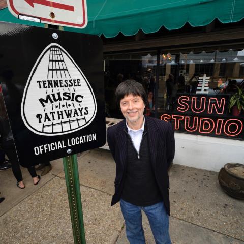 Ken Burns stands in front of a Tennessee Music Pathways sign