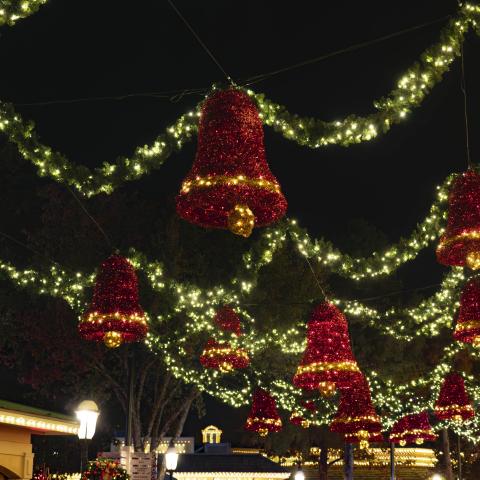 bright shining lights hung in garland at Smoky Mountain Christmas at Dollywood. It's nighttime and the lights are hung across building tops illuminating the walkway.  